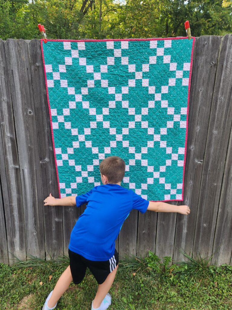 boy holding the bottom of a quilt